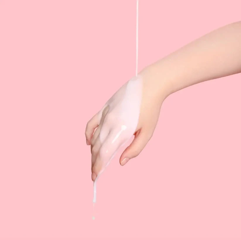 Hand holding a thin white string against a pink background