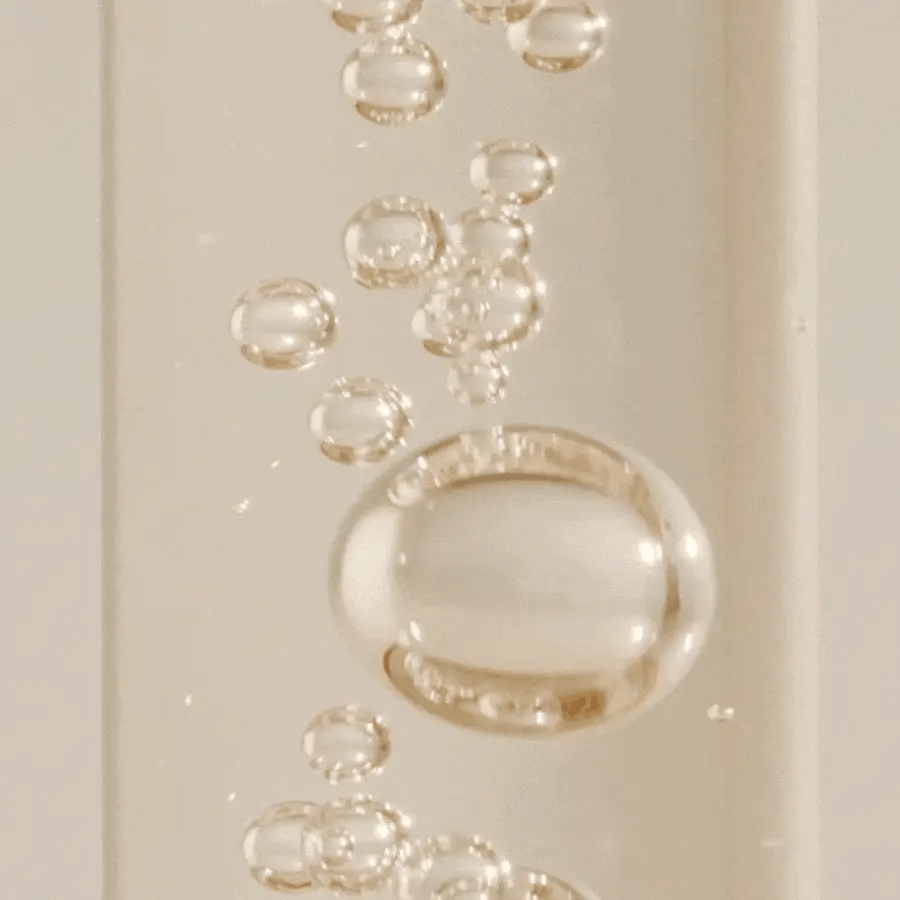 Close-up of a gold ring with bubbles on a beige background