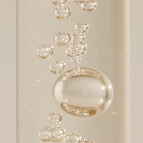 Close-up of a gold ring with bubbles on a beige background
