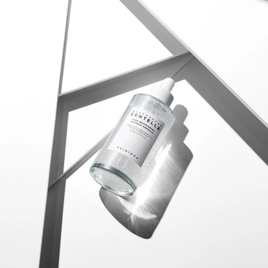 Skincare bottle with a white cap on a gray geometric background