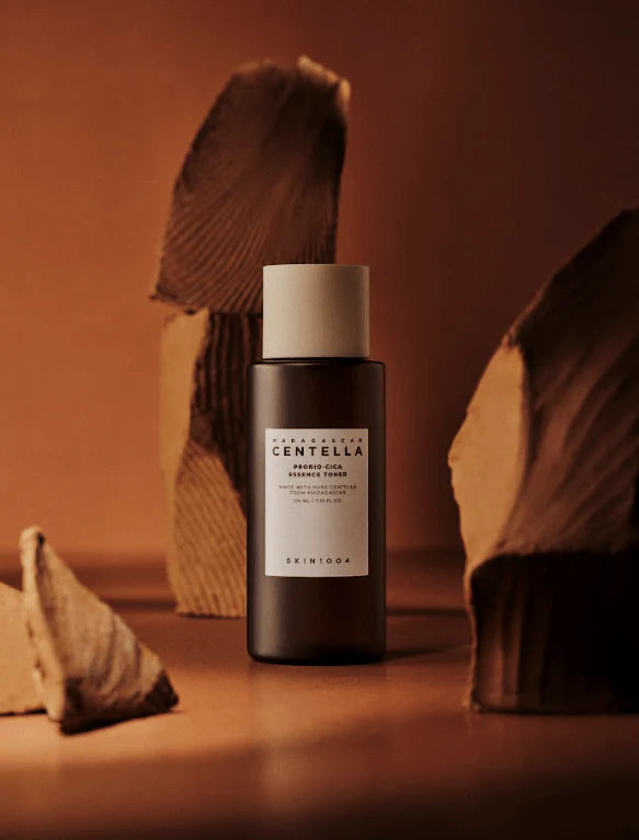 Skincare bottle labeled Probio-Cica Essence Toner on a brown background with natural elements.